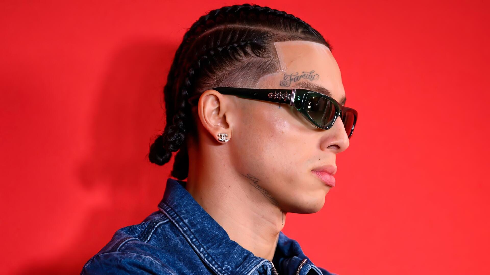 HD PC desktop wallpaper: portrait of a young British man in cornrows and sunglasses, sporting urban rap-style fashion against a vibrant red background.
