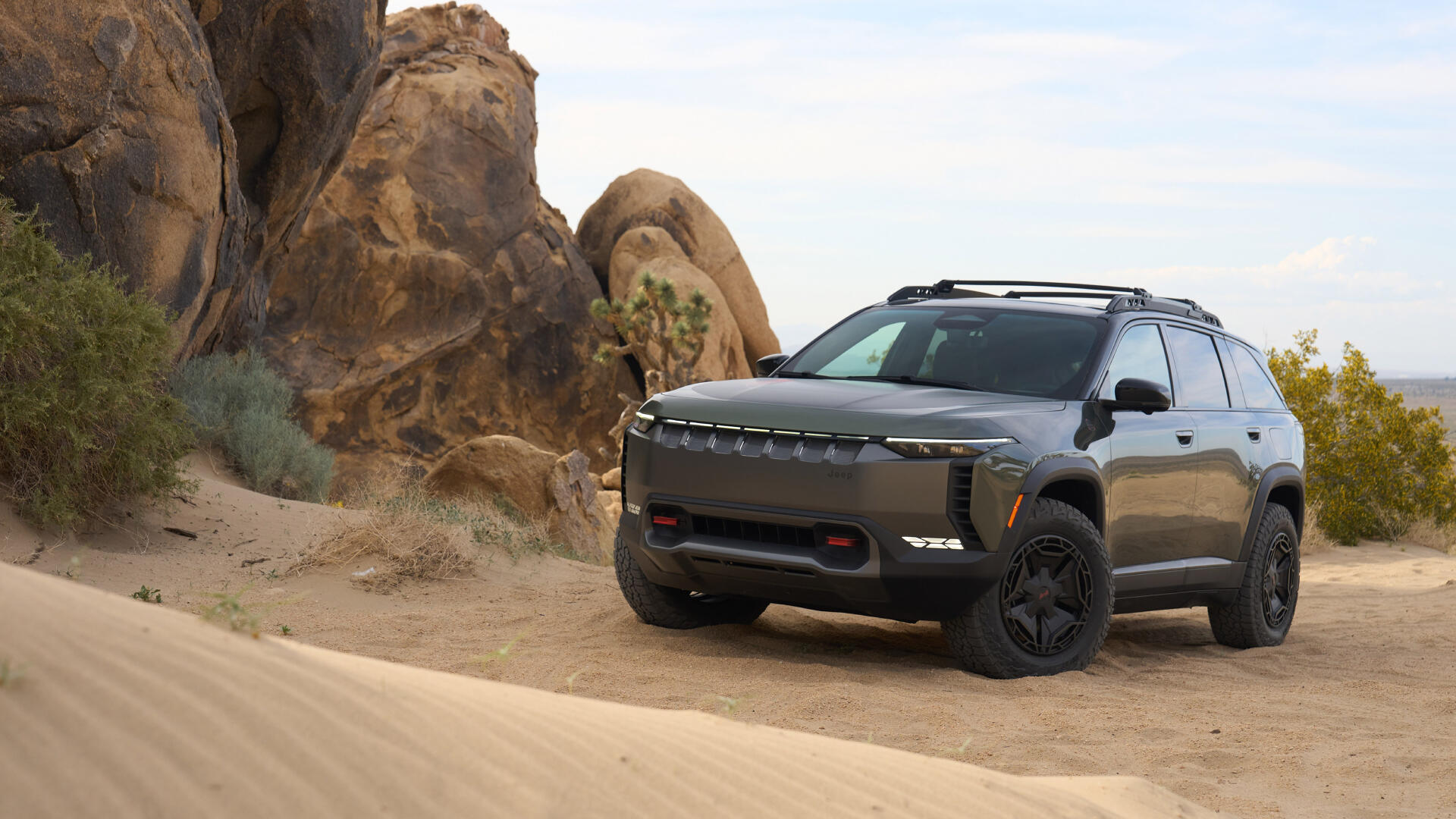 4K Ultra HD PC desktop wallpaper: Jeep Wagoneer S SUV vehicle on sand amid rocky desert formations.