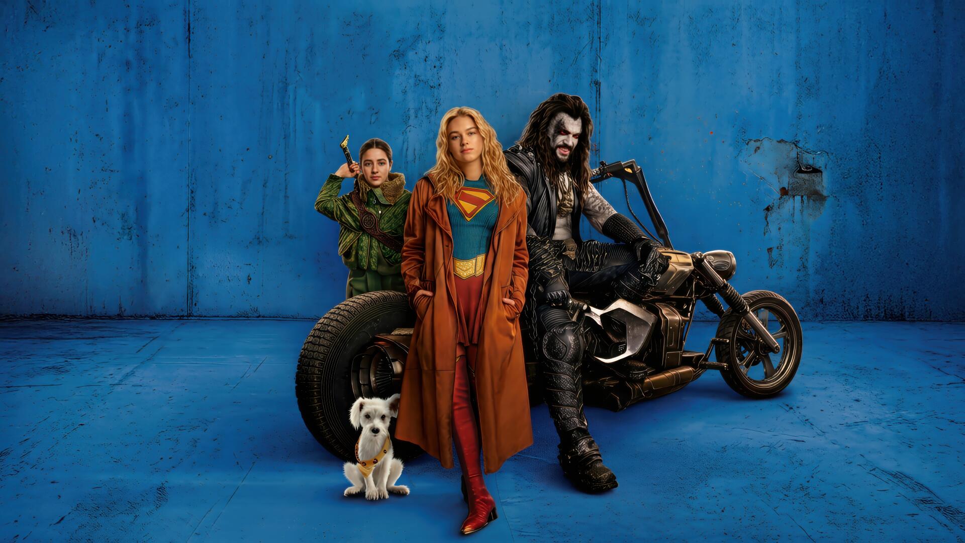 Supergirl (2026) 4K Ultra HD PC desktop wallpaper: Supergirl in red-and-blue suit and leather jacket stands center, flanked by an archer ally, a leather-clad biker on a motorcycle, and a small dog.