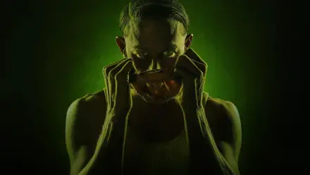 HD PC desktop wallpaper titled Monster: The Ed Gein History — eerie green-lit figure lifting a mask, gaunt arms and a shadowed, intense stare.