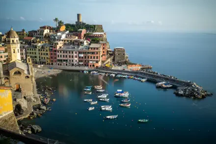 4K Ultra HD PC desktop wallpaper: Mediterranean Liguria village landscape in Italy — colorful coastal houses and church on a rocky harbor with boats on calm blue sea.