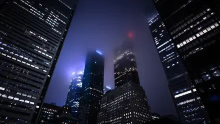Night photography of Tokyo, Japan skyscrapers rising into mist, illuminated windows and neon glow — 4K Ultra HD PC desktop wallpaper and background.