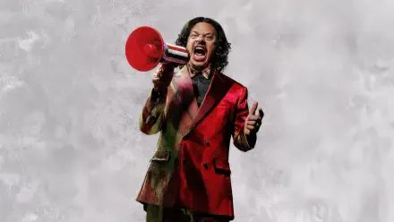 Street Fighter (2026) 5K Ultra HD PC desktop wallpaper: a person in a red suit shouting into a red megaphone against a cloudy gray backdrop.