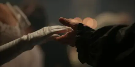 2K Quad HD Bridgerton TV show desktop wallpaper: a gloved hand and a bare hand reach to touch in a dim, intimate ballroom scene.