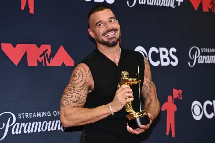Celebrity musician (identity not disclosed) smiles holding an MTV Video Music Awards Moon Person trophy against a branded backdrop — 2K Quad HD PC desktop wallpaper/background.