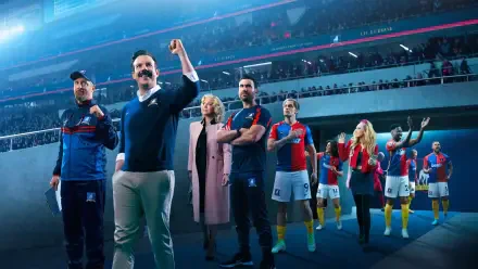 4K Ultra HD PC wallpaper of Ted Lasso and his team entering a packed stadium: coach raising a fist while players and staff follow under bright stadium lights.