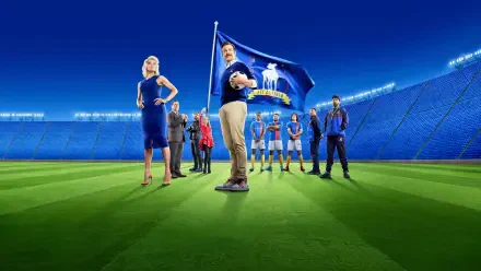 Ted Lasso 4K Ultra HD PC desktop wallpaper: the coach stands center holding a soccer ball, flanked by teammates and staff on a brightly lit stadium pitch under night lights.