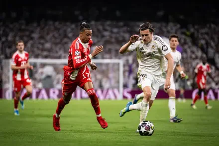 4K Ultra HD desktop wallpaper: soccer action — FC Bayern Munich player in red races a Real Madrid player in white for the ball on a packed stadium pitch.