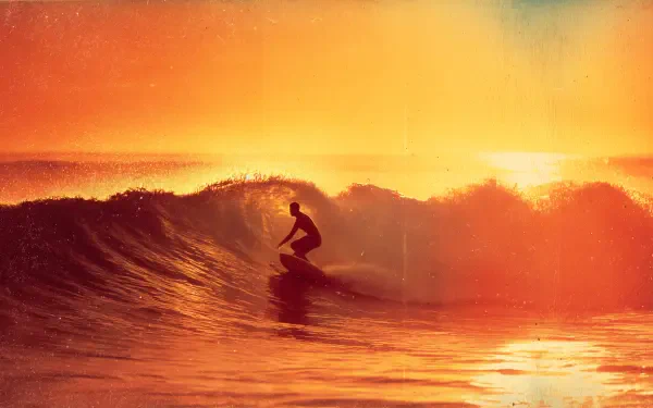 Silhouetted surfer carving a glowing orange wave at sunset — 4K Ultra HD PC desktop wallpaper/background featuring surfing and a dramatic ocean wave.