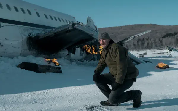 5K Ultra HD desktop wallpaper: a kneeling actor from the TV show The Last Frontier beside a burning, crashed airliner on a snowy tundra beneath a pale blue sky.