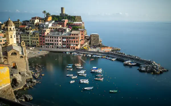 4K Ultra HD PC desktop wallpaper: Mediterranean Liguria village landscape in Italy — colorful coastal houses and church on a rocky harbor with boats on calm blue sea.