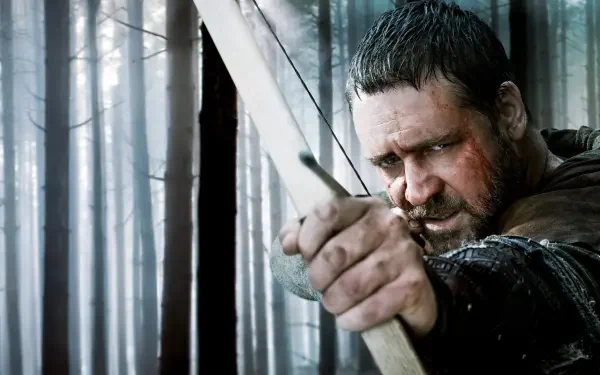 Robin Hood (2010) 4K Ultra HD PC desktop wallpaper — close-up of Robin Hood drawing a bow in a misty pine forest, his face streaked with mud and rain.