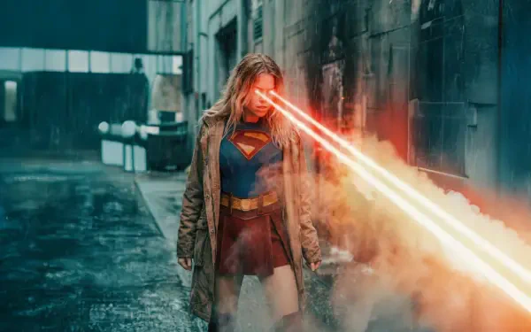Supergirl (2026) 5K Ultra HD PC desktop wallpaper/background: Supergirl in a coat over her suit, unleashing intense red heat-vision down a smoky urban alley.
