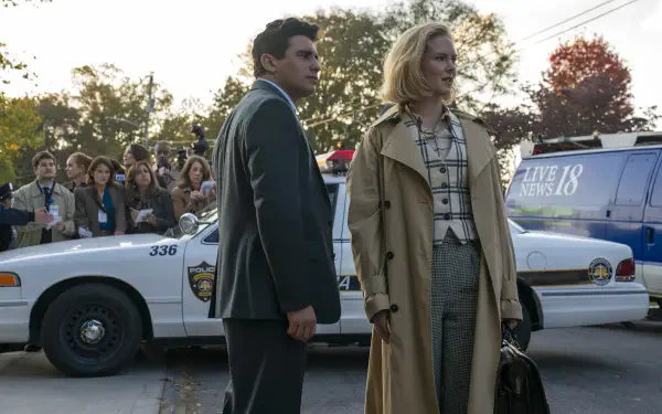 TV show Scarpetta scene with two lead actors by police cars and a gathered crowd in autumn light — 2K Quad HD PC desktop wallpaper/background.