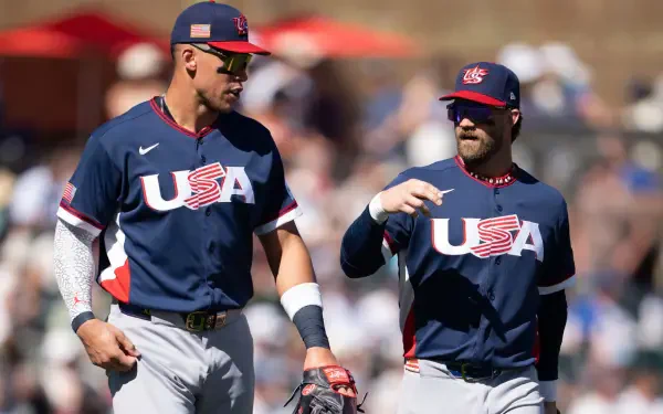 HD PC desktop wallpaper: two USA Baseball players in navy USA uniforms walking and talking across a sunlit stadium field.