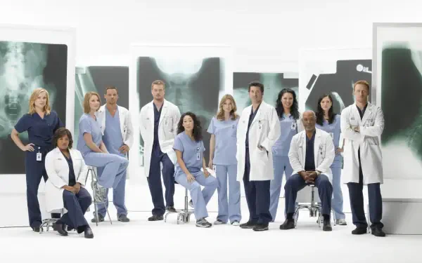 HD PC desktop wallpaper for the TV show Grey's Anatomy showing a group of doctors in scrubs and white coats posed in front of large chest X-ray panels.