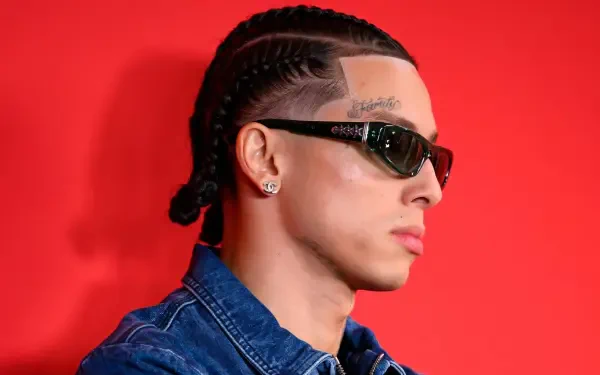 HD PC desktop wallpaper: portrait of a young British man in cornrows and sunglasses, sporting urban rap-style fashion against a vibrant red background.