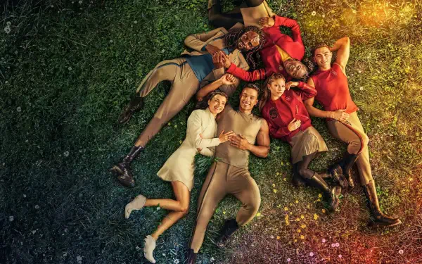 Star Trek: Starfleet Academy 2K Quad HD PC desktop wallpaper and background showing cadets in colorful uniforms lying in a circle on grass, smiling beneath warm sunlight and scattered sparkles.