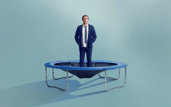 4K Ultra HD PC Desktop Wallpaper and Background: man stands on a small trampoline in a pale teal room, conveying a surreal shrinking theme.