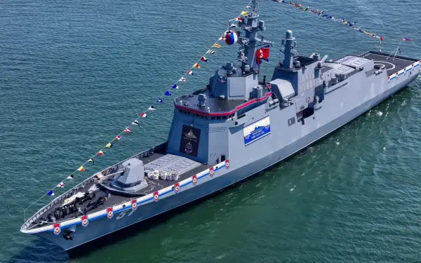 HD desktop wallpaper: North Korean Choe Hyon-class guided-missile destroyer at sea, deck draped in signal flags during a military naval fleet ceremony.