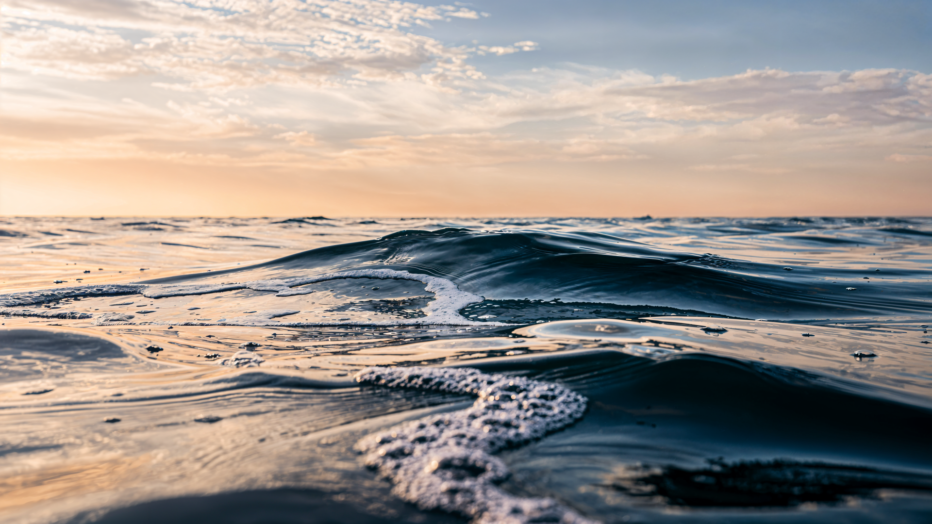 Close-up ocean waves under a pastel sunrise along the distant horizon — 4K Ultra HD PC desktop wallpaper.