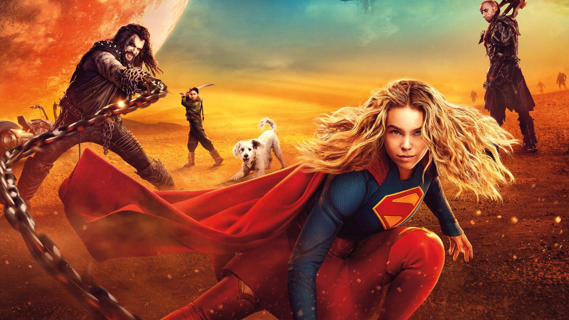 Supergirl (2026) crouches with her red cape billowing against a golden-orange sunset, allies and a white dog in the distance — 4K Ultra HD PC desktop wallpaper/background.