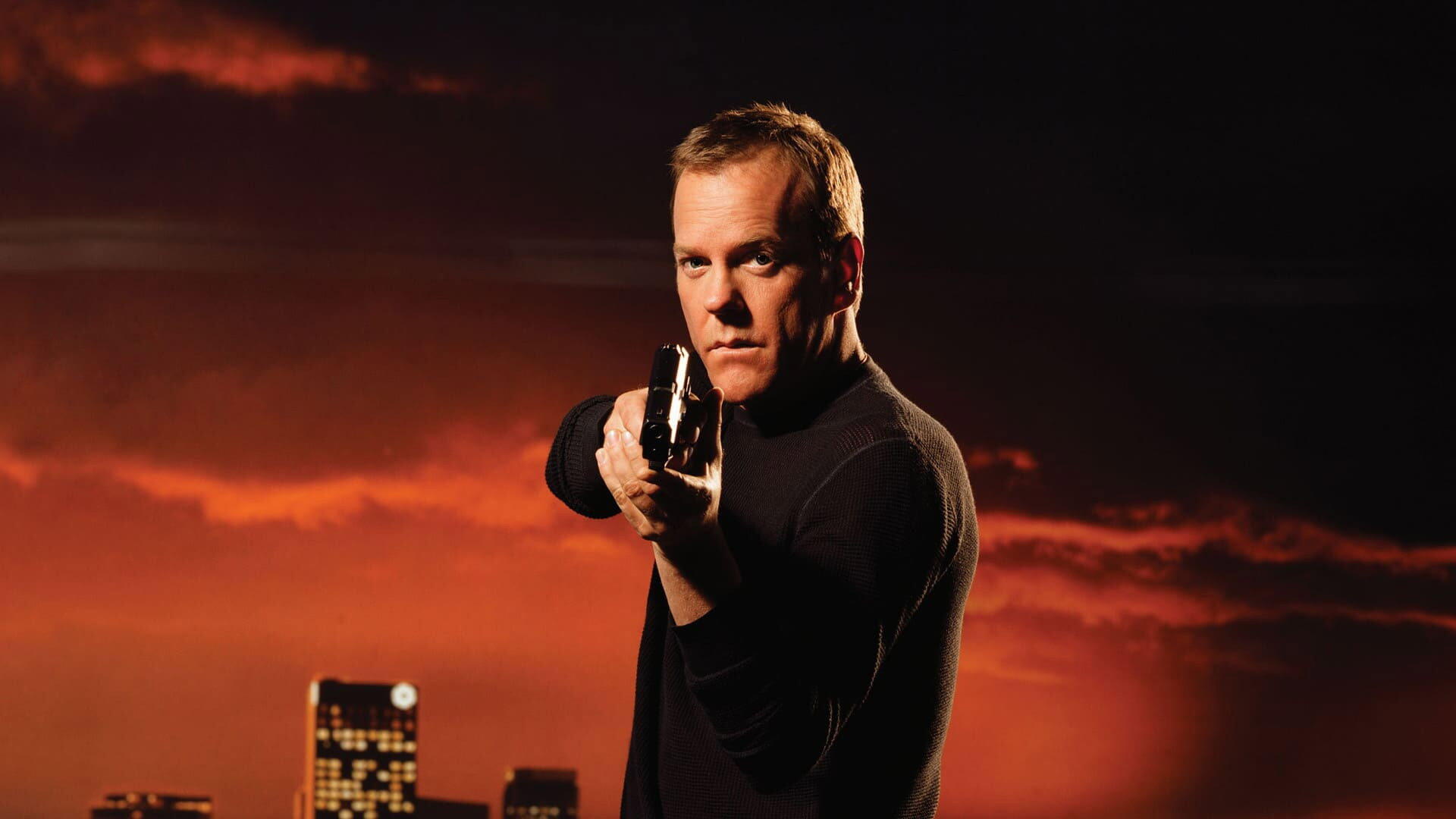 HD PC desktop wallpaper/background (tagged 24): intense man in black aiming a handgun toward the viewer, orange-red sky and silhouetted city skyline behind him.