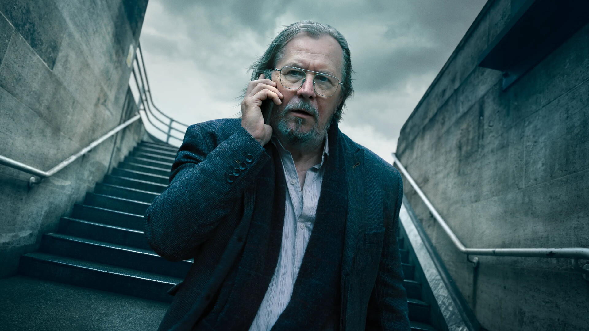 Gritty portrait of a disheveled older man on concrete stairs, speaking on a phone — Slow Horses 4K Ultra HD PC desktop wallpaper and background.