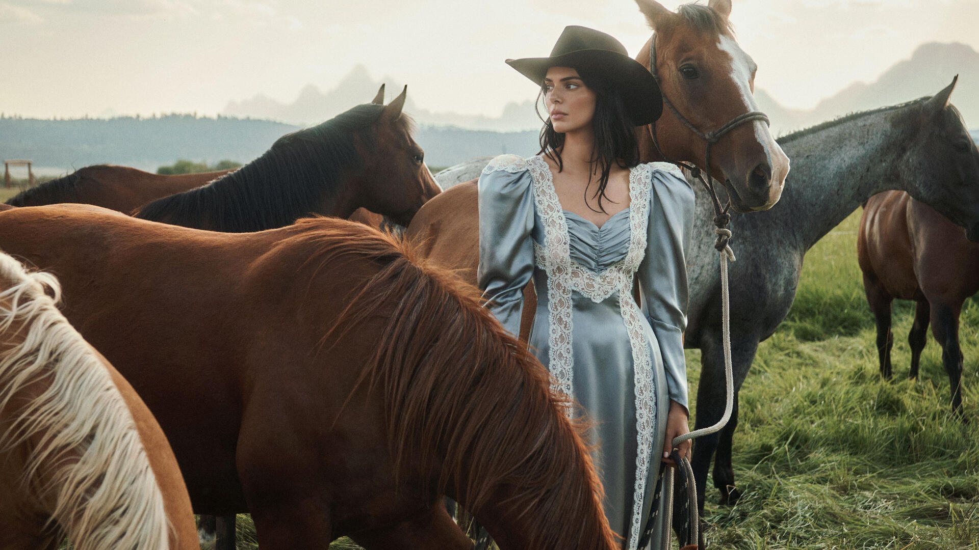 2K Quad HD PC desktop wallpaper: a model in a flowing vintage gown and wide-brim hat stands among grazing horses in a misty meadow.