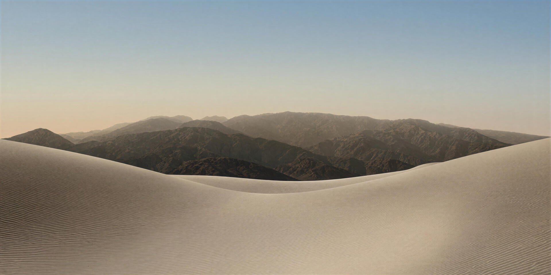 Minimal 4K Ultra HD PC desktop wallpaper: smooth desert dunes in foreground with layered mountain ridges under a soft gradient sky, tagged iPhone Duo and computer.