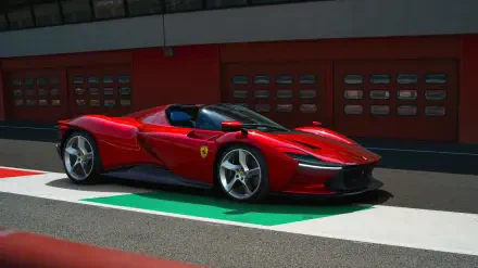 Red Ferrari Daytona SP3 vehicle on a racetrack pit lane, rendered as a 2K Quad HD PC desktop wallpaper background.
