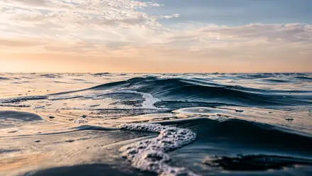 Close-up ocean waves under a pastel sunrise along the distant horizon — 4K Ultra HD PC desktop wallpaper.