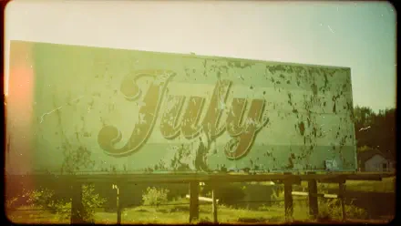 Weathered billboard with cursive July amid sunlit, faded green-yellow tones — 4K Ultra HD PC desktop wallpaper and background.