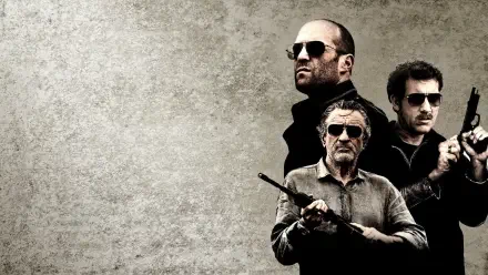 Killer Elite HD PC desktop wallpaper: three armed men in dark clothing and sunglasses clustered at right against a textured gray background.