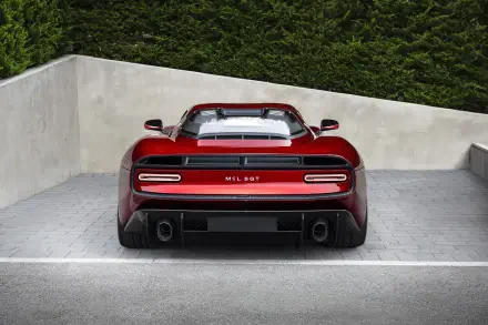 Rear view of a red McLaren McL 6GT sports supercar parked against a concrete wall, rendered as an 8K Ultra HD PC desktop wallpaper/background.