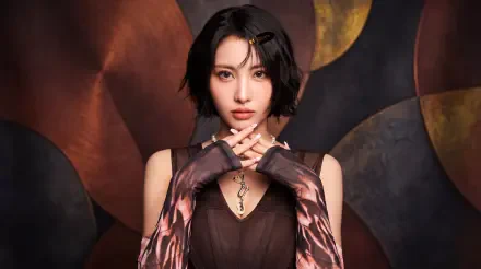 Close-up portrait of a short-haired woman posed like a k-pop idol/Japanese model, wearing patterned gloves and a dark dress against a warm abstract backdrop; 5K desktop wallpaper.