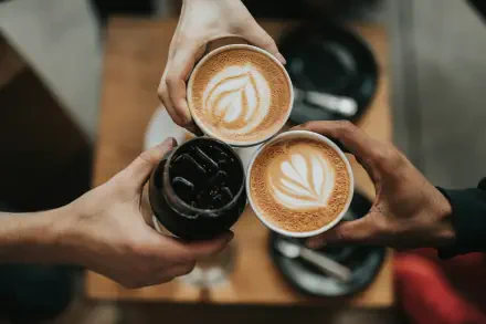 Espresso Fall cozy 4K Ultra HD PC desktop background: three coffee cups — two lattes with heart latte art and one iced espresso — held over a wooden table.