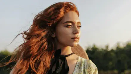 Portrait of a red‑haired girl model gazing toward sunset; 4K Ultra HD PC desktop wallpaper and background with warm golden‑hour light and soft bokeh.