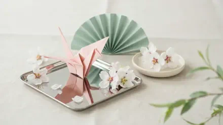 2K Quad HD spring aesthetic desktop wallpaper: pink origami crane and paper flowers on a mirrored tray with a mint paper fan against a soft neutral backdrop.