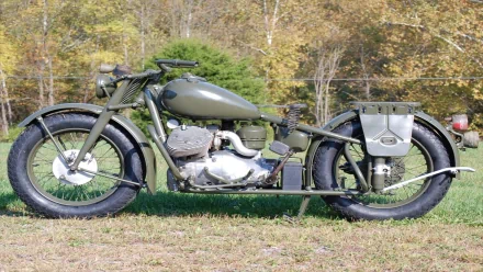 HD PC desktop wallpaper featuring a vintage Indian 841 motorcycle parked on grass with a forest backdrop, showcasing its classic military-style design and muted green color.