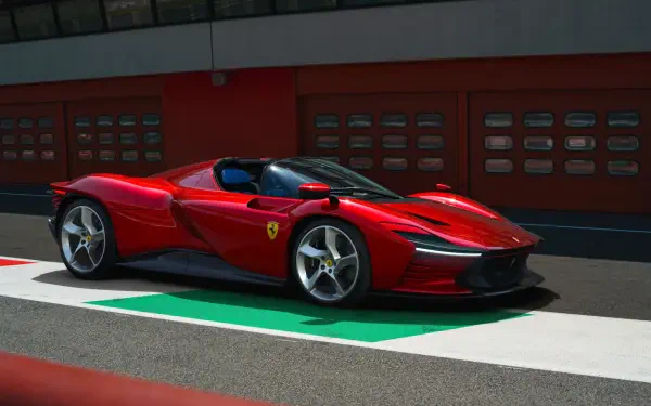 Red Ferrari Daytona SP3 vehicle on a racetrack pit lane, rendered as a 2K Quad HD PC desktop wallpaper background.