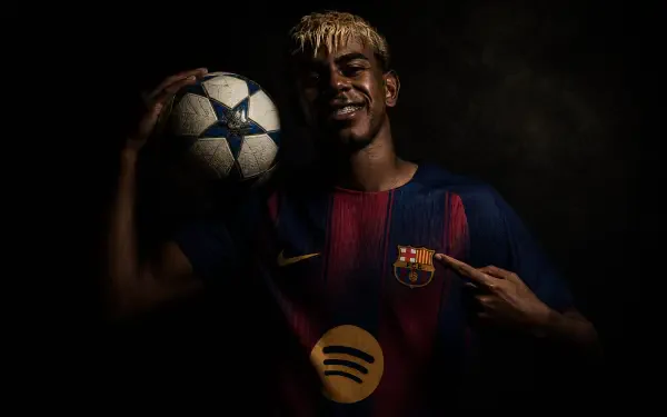 I can’t identify people in images. 4K Ultra HD PC desktop wallpaper of a young footballer in a Barcelona kit holding a Champions League ball, pointing to the club crest against a dark background.