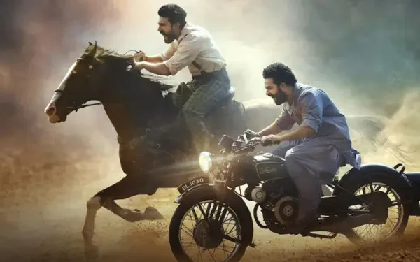 4K Ultra HD PC wallpaper — RRR action: man on a galloping horse racing alongside another on a vintage motorcycle through dusty, golden light.