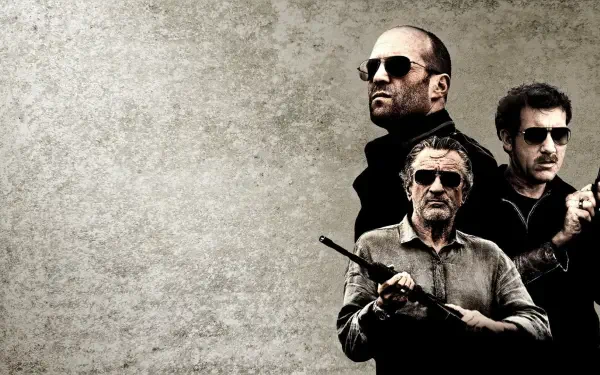 Killer Elite HD PC desktop wallpaper: three armed men in dark clothing and sunglasses clustered at right against a textured gray background.