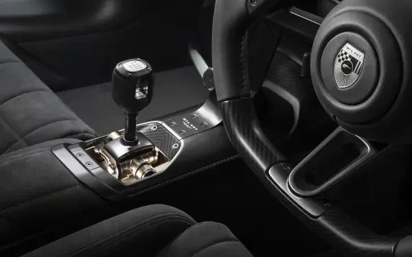 8K Ultra HD wallpaper of McLaren McL 6GT interior, close-up of steering wheel, gated gear shifter and quilted leather upholstery.