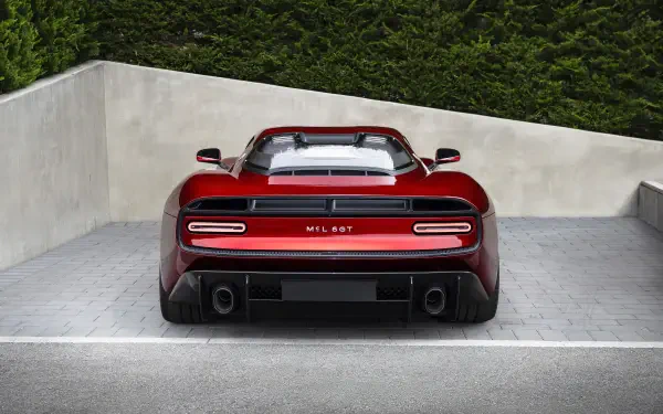 Rear view of a red McLaren McL 6GT sports supercar parked against a concrete wall, rendered as an 8K Ultra HD PC desktop wallpaper/background.