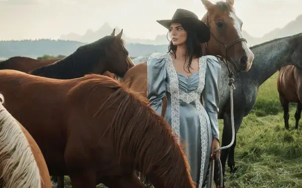 2K Quad HD PC desktop wallpaper: a model in a flowing vintage gown and wide-brim hat stands among grazing horses in a misty meadow.