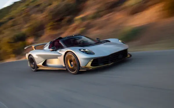 Silver Aston Martin Valhalla Spider supercar racing along a road, featured in an 8K Ultra HD desktop wallpaper.