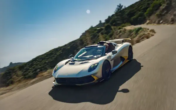 Aston Martin Valhalla Spider sports car racing along a mountain road in an 8K Ultra HD desktop wallpaper.