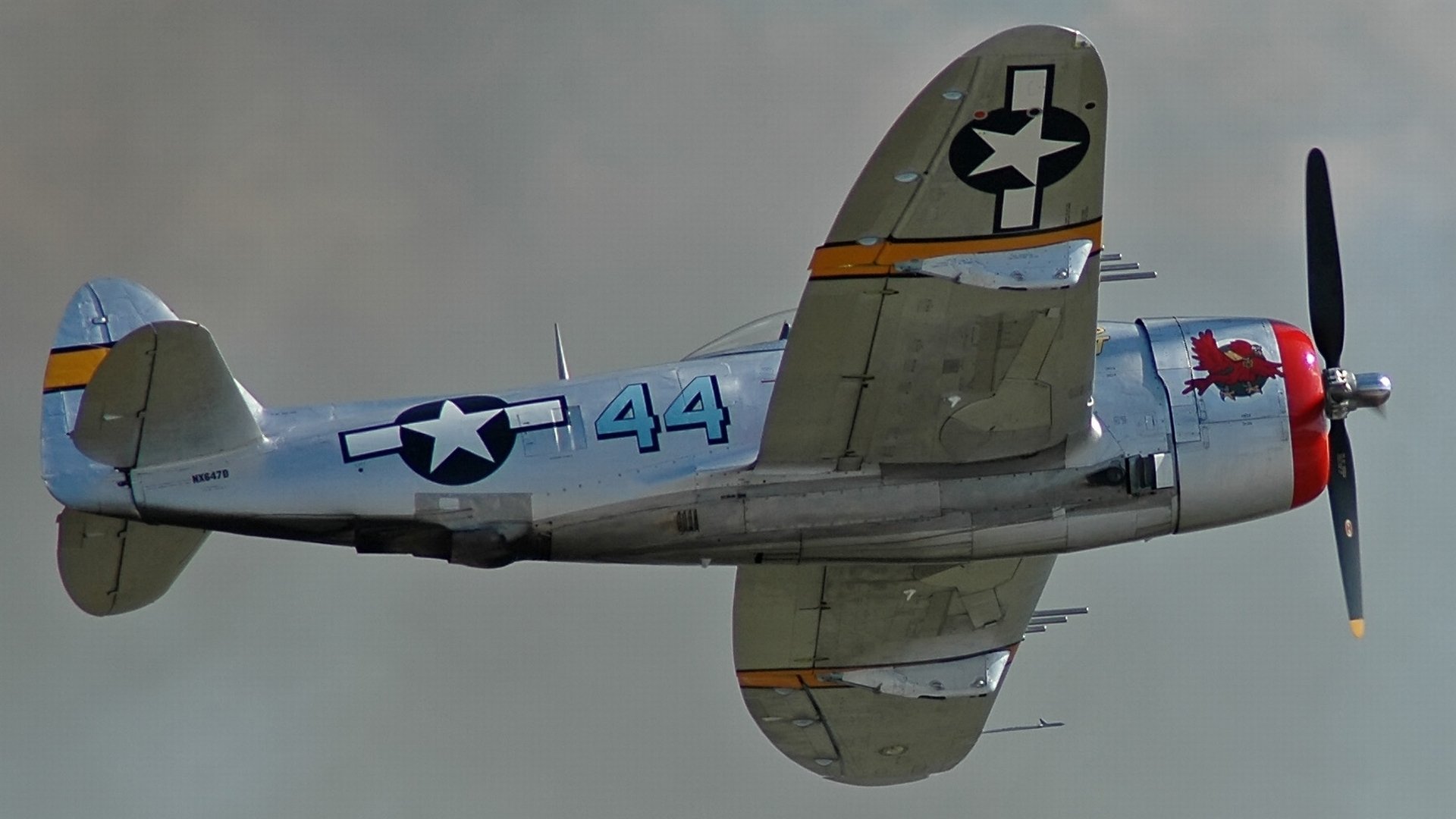 HD PC desktop wallpaper featuring a vintage military aircraft in flight, showcasing detailed markings and a gray-blue sky background.